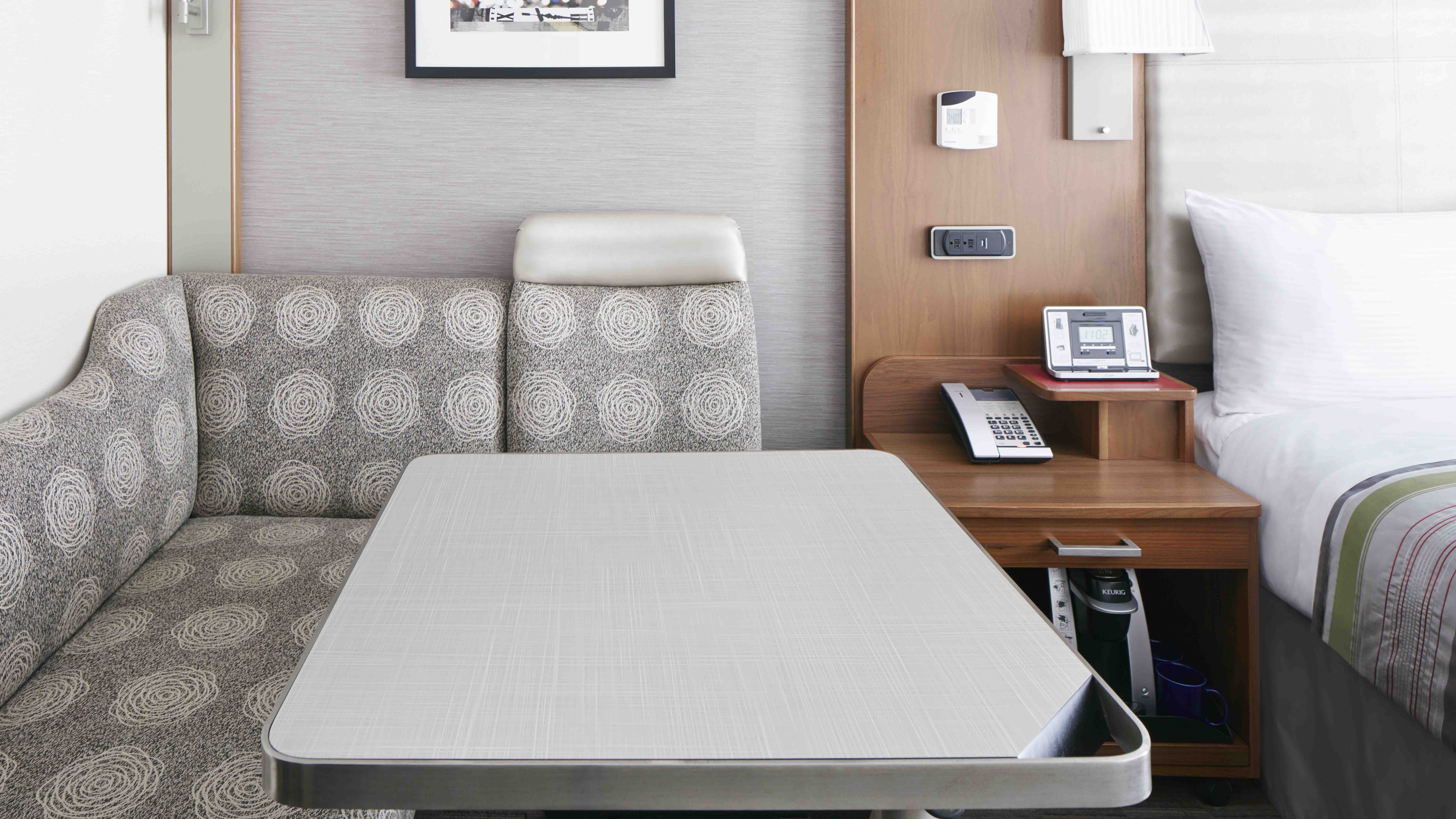 A hotel room with a sofa, bed, and nightstand
