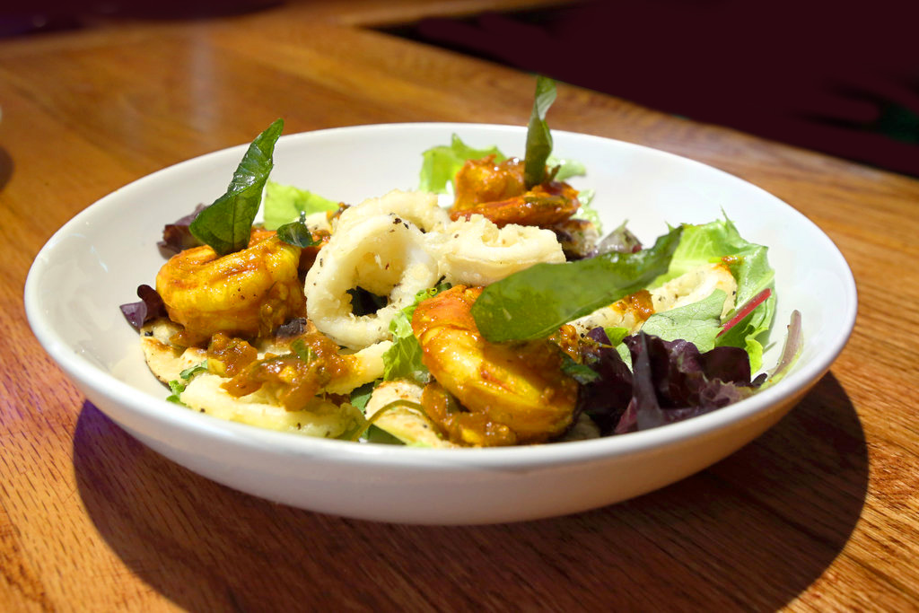 a white bowl of salad with shrimp on a wooden table
